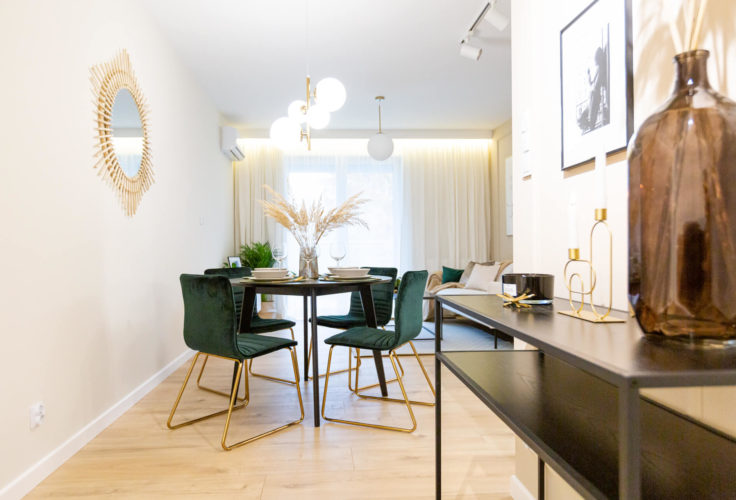 krzesła w butelkowej zieleni, czarny okrągły stół, czarna konsola, mieszkanie pod klucz