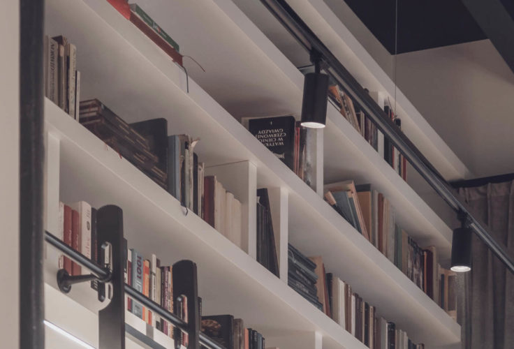 klimat wnętrza, przytulny salon, drewniana podłoga, obraz, plakat na ścianie, styl industrialny, biblioteka w domu